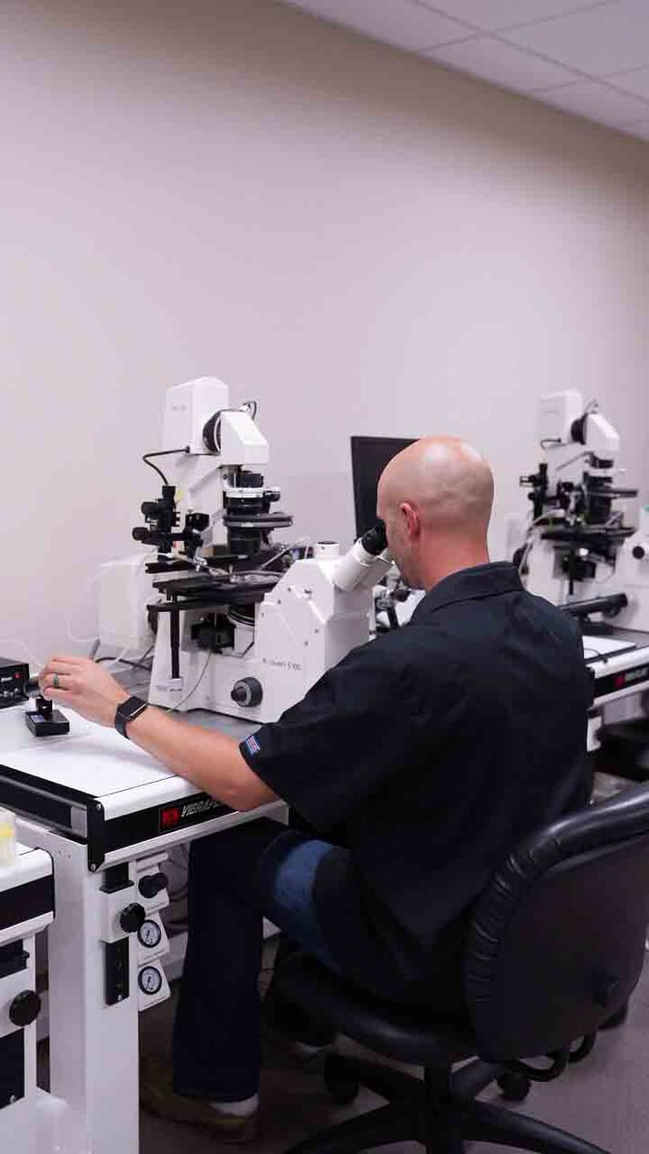 A scientist examines samples using a microscope in a lab, focusing intently on the research work at hand.