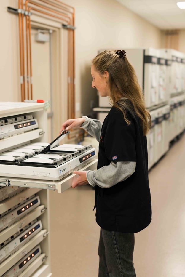 Lab technician loading samples into laboratory testing equipment.